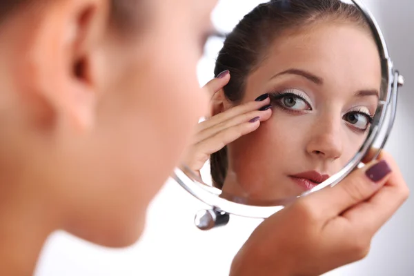 Beautiful girl preens before small mirror isolated on white — Stock Photo, Image