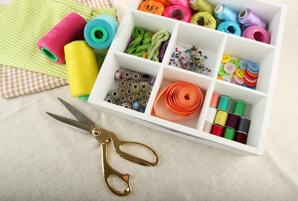 Herramientas y materiales para coser en caja sobre fondo de tela — Foto de Stock