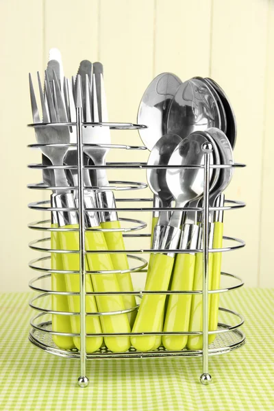 Cuchillos, tenedores y cucharas en soporte de metal sobre mantel sobre fondo beige —  Fotos de Stock