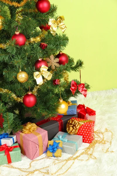 Yeşil duvar arka plan üzerinde hediyeler ile Noel ağacı süslü — Stok fotoğraf