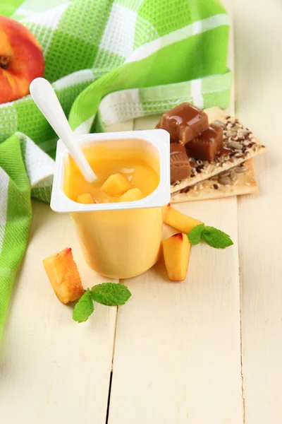 Sabroso yogur con trozos de fruta fresca, galletas y copos, sobre fondo de madera de color —  Fotos de Stock