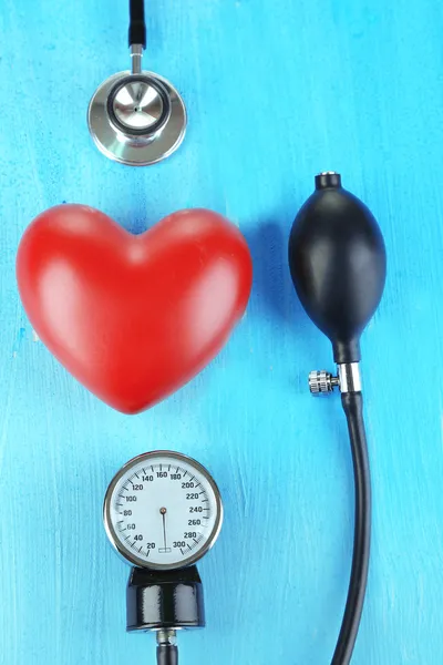 Tonometer, stethoscope and heart on wooden table close-up — Stock Photo, Image