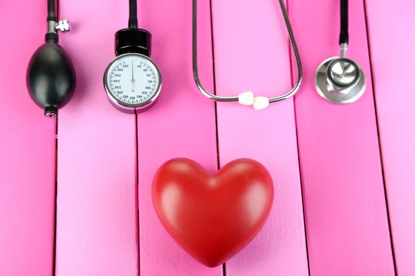 Tonometer, Stethoskop und Herz auf Holztisch in Großaufnahme — Stockfoto