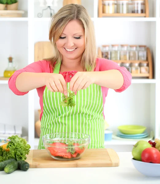 Glada leende kvinna i köket förbereder grönsakssallad — Stockfoto