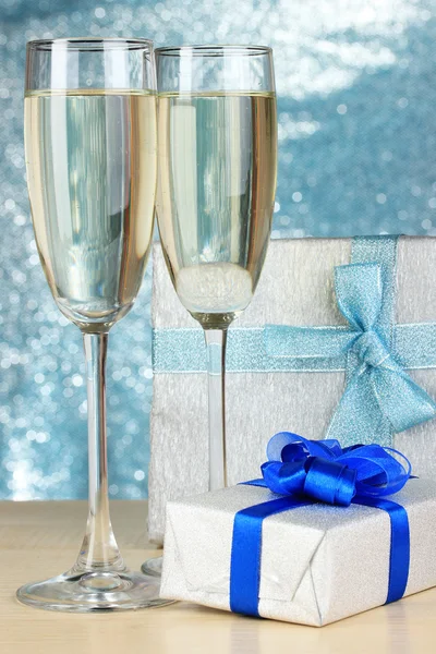 Copos de champanhe com caixas de presente em fundo brilhante — Fotografia de Stock