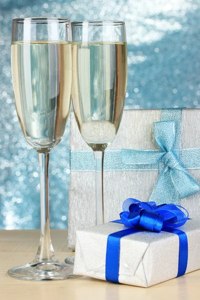 Glasses of champagne with gift boxes on shiny background — Stock Photo, Image