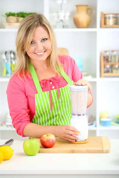 Šťastná usměvavá žena v kuchyni připravuje čerstvé ovoce koktejl — Stock fotografie