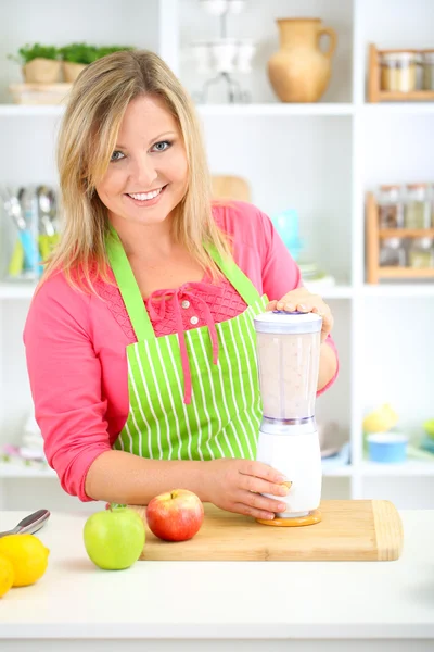 Happy smiling woman in kitchen preparing fresh fruit cocktail — Stock Photo, Image