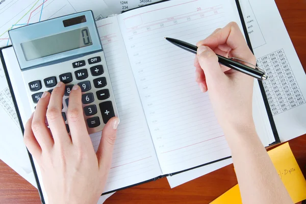Mujer manos contando con calculadora en fondo de mesa de trabajo —  Fotos de Stock