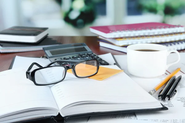 Materiales de oficina con documentos y taza de café en la mesa sobre fondo brillante — Foto de Stock