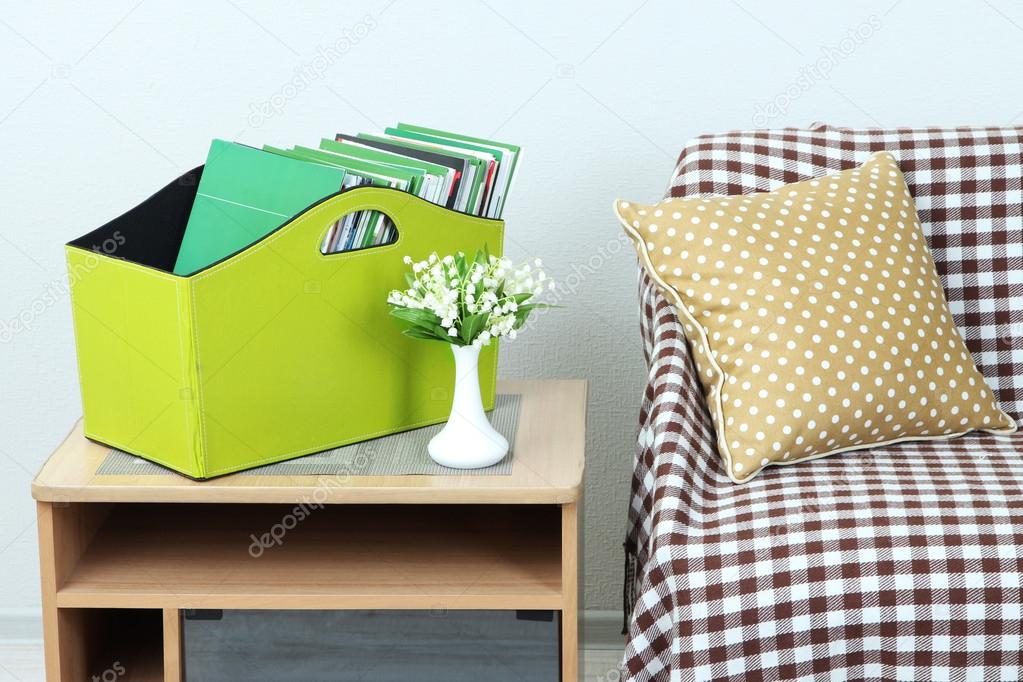 Magazines and folders in green box on bedside table in room
