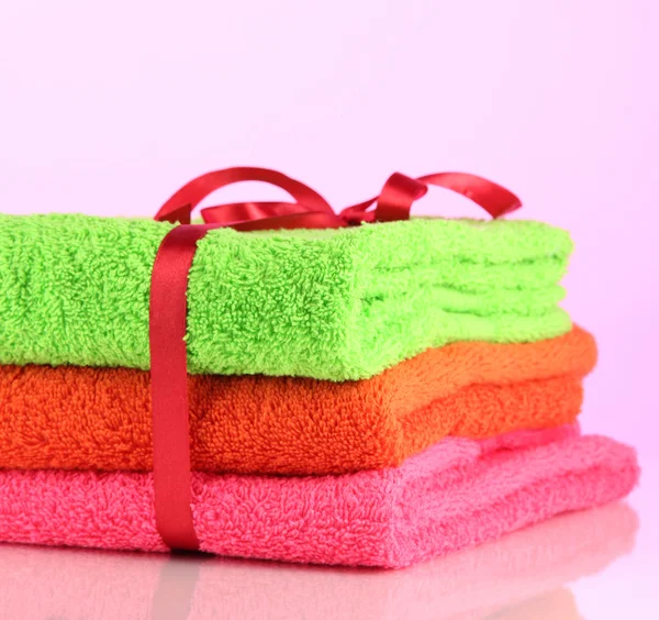 Towels tied with ribbon on light pink background — Stock Photo, Image