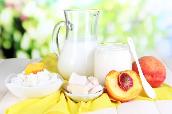 Fresh dairy products with peaches on wooden table on natural background — Stock Photo, Image