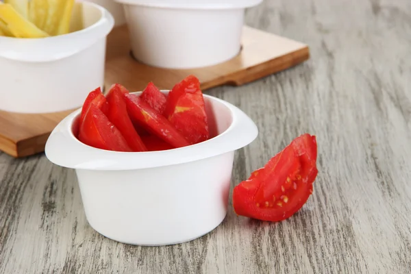 Bright fresh vegetables cut up slices in bowls on wooden table close-up