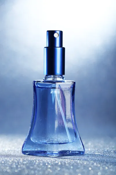 Perfume de mujer en hermosa botella sobre fondo azul —  Fotos de Stock