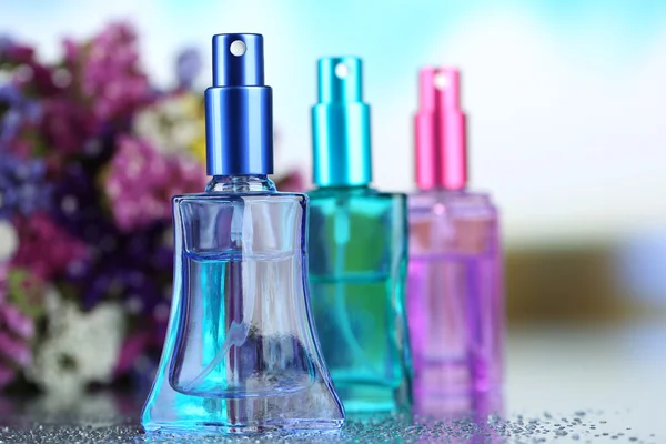 Perfume de mujer en hermosas botellas y flores — Foto de Stock