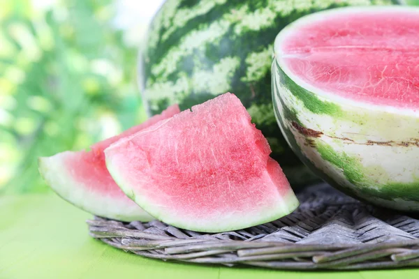 Ripe watermelons on wicker tray on wooden table on nature background — Stock Photo, Image