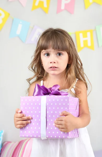 Niña con regalo en la habitación sobre fondo de pared gris — Foto de Stock