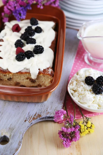 Cheese casserole with raisins in pan on napkin on wooden table close-up — Stock Photo, Image