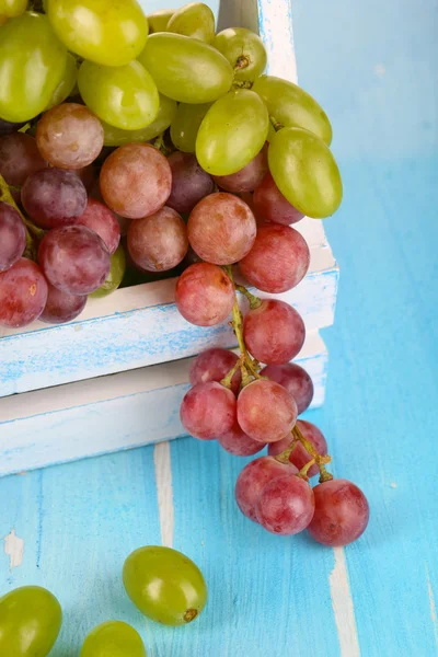 Ripe green and purple grapes in basket on wooden table close-up — Stock Photo, Image