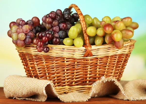 在明亮的背景上的柳条垫上的新鲜葡萄 — 图库照片