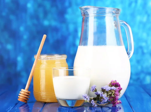 Honey and milk on wooden table on blue background — Stock Photo, Image