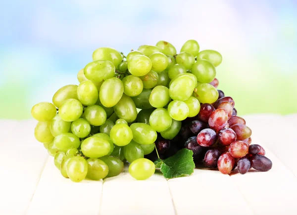Rijp groene en paarse druiven op houten tafel op natuurlijke achtergrond — Stockfoto