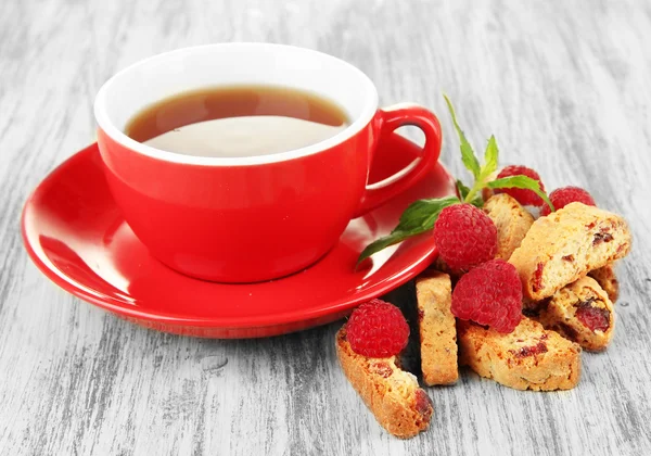 Cup of tea with cookies and raspberries on table close-up