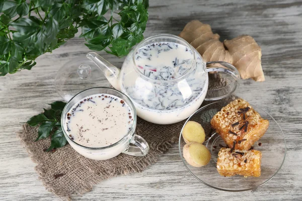 Bule e xícara de chá com leite e especiarias em saco de mesa de madeira — Fotografia de Stock