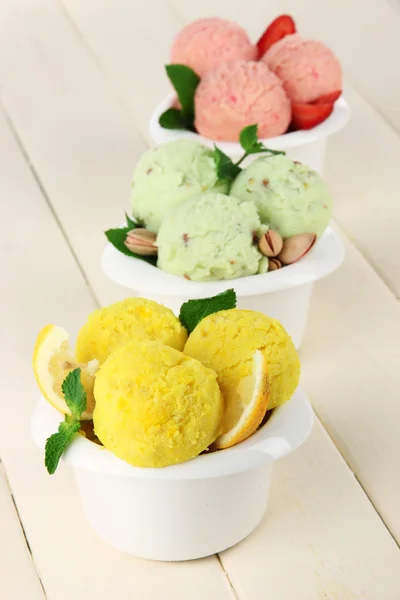 Tasty ice cream scoops in bowls, on wooden table — Stock Photo, Image