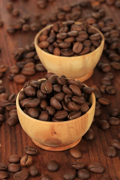 Koffie bonen in kommen op houten achtergrond — Stockfoto