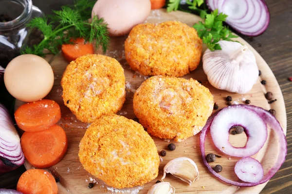 Meat patties on board on wooden table — Stock Photo, Image