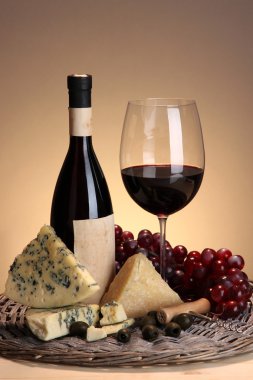 şarap, peynir ve üzüm hasır tepsi ahşap masanın üzerine bej renkli arka plan üzerinde siyah zemin natürmort