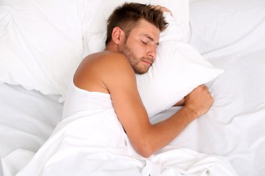 Yakışıklı genç adam yatakta.