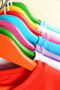 bej renkli arka plan üzerinde renkli askı üzerinde farklı gömlek