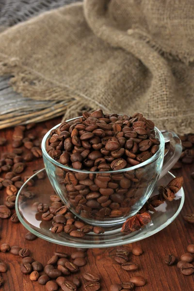 Kaffeebohnen in Tasse auf Holzgrund — Stockfoto