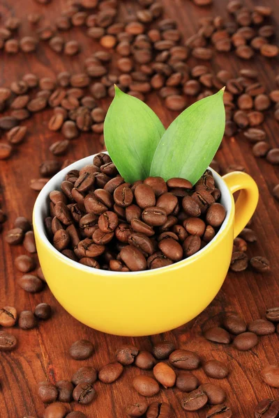 木製の背景の上にカップのコーヒー豆 — ストック写真