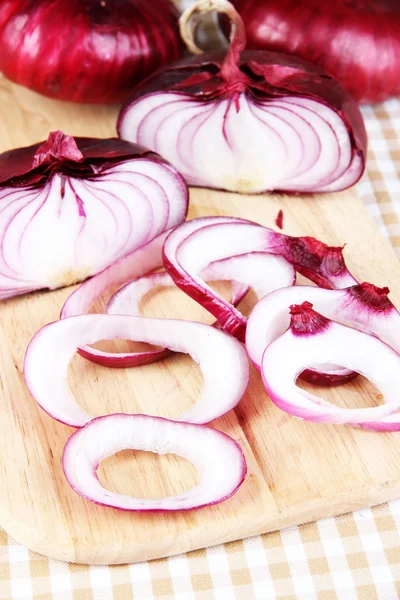 Cebollas rojas frescas en la tabla de cortar de cerca — Foto de Stock