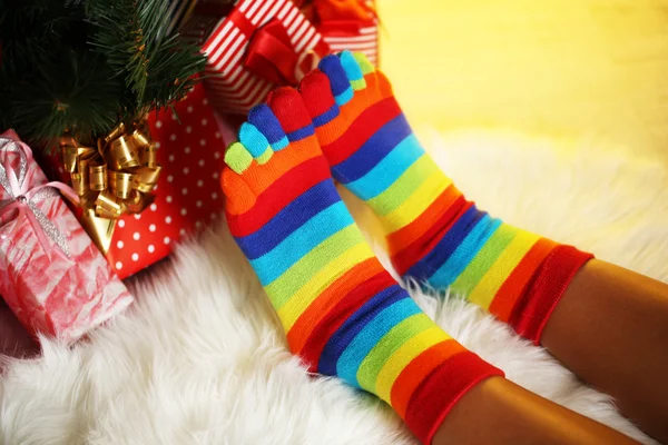 Benen in sokken in de buurt van de kerstboom op carped — Stockfoto