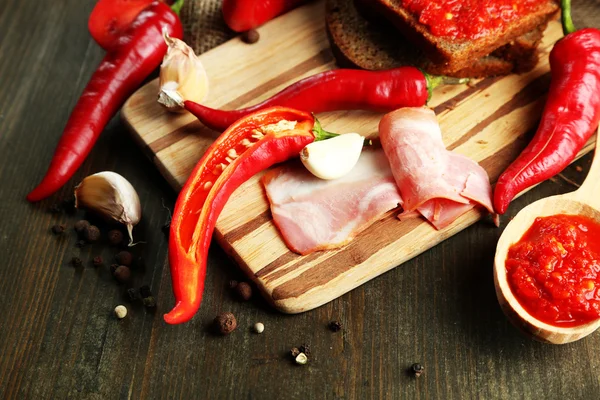 Samenstelling met salsa saus op brood,, red hot chili peppers en knoflook, op rouwgewaad, op houten achtergrond — Stockfoto