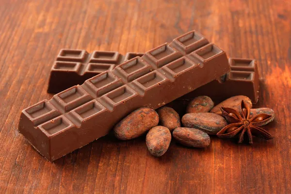 Ahşap zemin üzerine kakao çekirdekleri ile lezzetli çikolata bar — Stok fotoğraf
