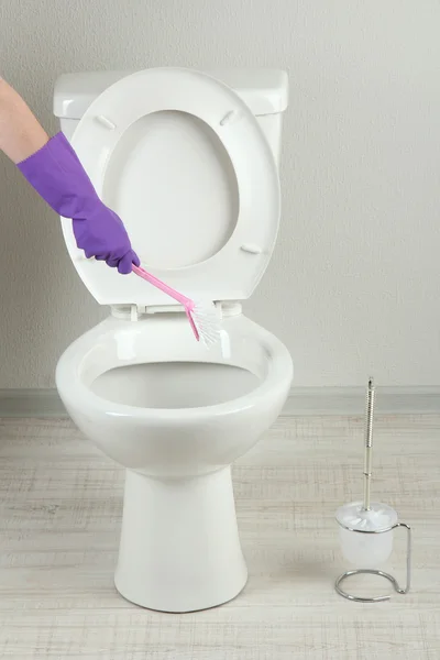 Woman hand with brush cleaning a toilet bowl in a bathroom — Stock Photo, Image