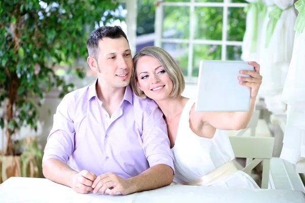 Pareja joven tomando fotos con la tableta en el restaurante — Foto de Stock