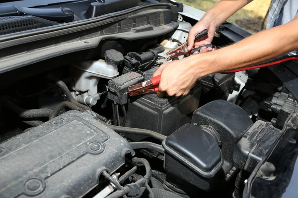 Mécanicien de voiture utilise des câbles de cavalier de batterie pour charger la batterie morte — Photo