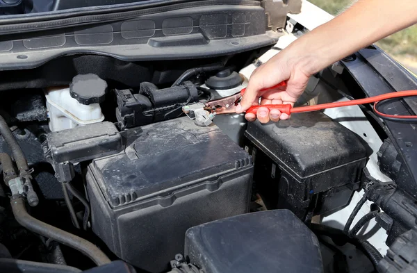 Car mechanic uses battery jumper cables to charge dead battery — Stock Photo, Image