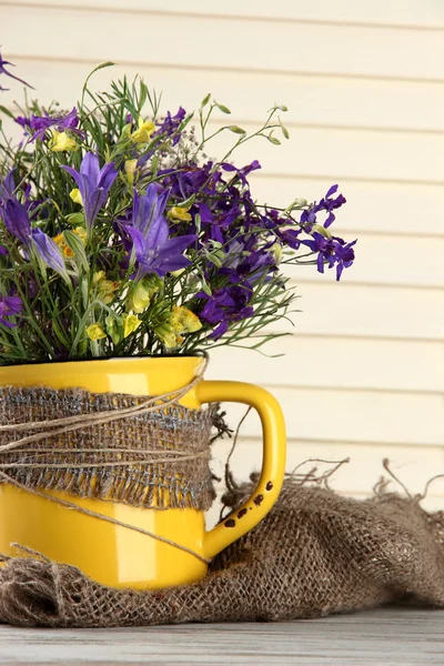 Mooi boeket van wilde bloemen in cup op houten tafel — Stockfoto