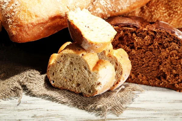 Much bread on sackcloth on wooden board — Stock Photo, Image