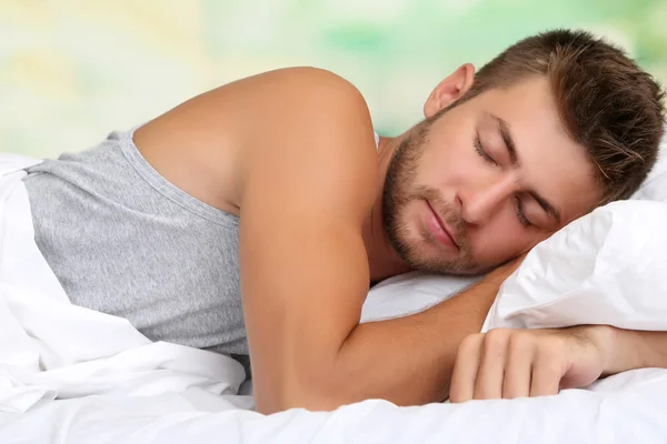 Bonito jovem na cama, no fundo brilhante, close-up — Fotografia de Stock