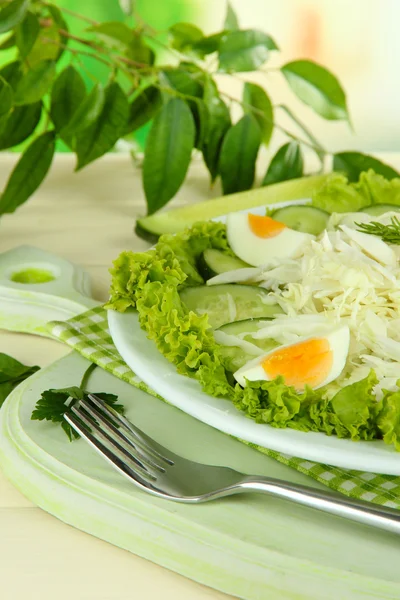 Delicious salad with eggs, cabbage and cucumbers on wooden table — Stock Photo, Image