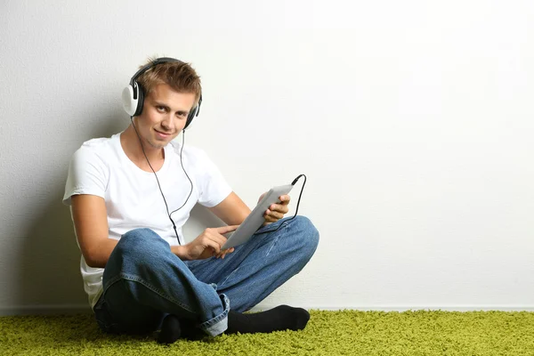 Junger Mann entspannt sich auf Teppich und hört Musik — Stockfoto